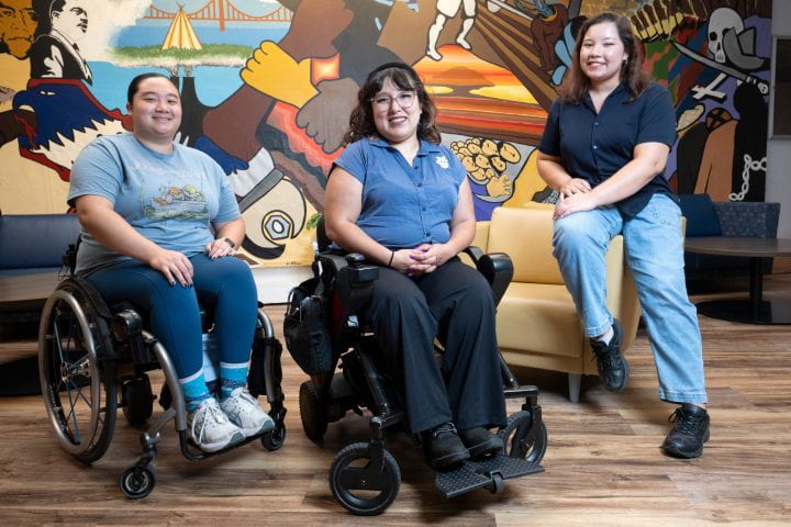 Naty Rico ’17, program director for UC Irvine’s Disability Cultural Center, is flanked by Alex Lee (left), a third-year genetics major, and Dani Galvan ’25 (right), a graduate student in informatics, at the new facility, which opened in February.